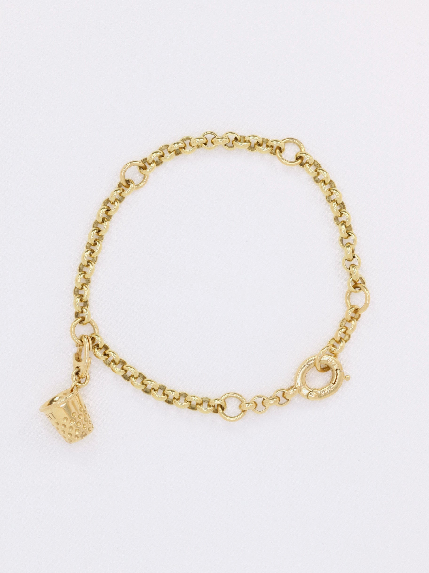 Bracelet en or 18k (750°/°°) composé d'une chaîne à maille ronde et d'un charms figurant un dé à coudre. Signé Dior 750 et numéroté sur le fermoir. 