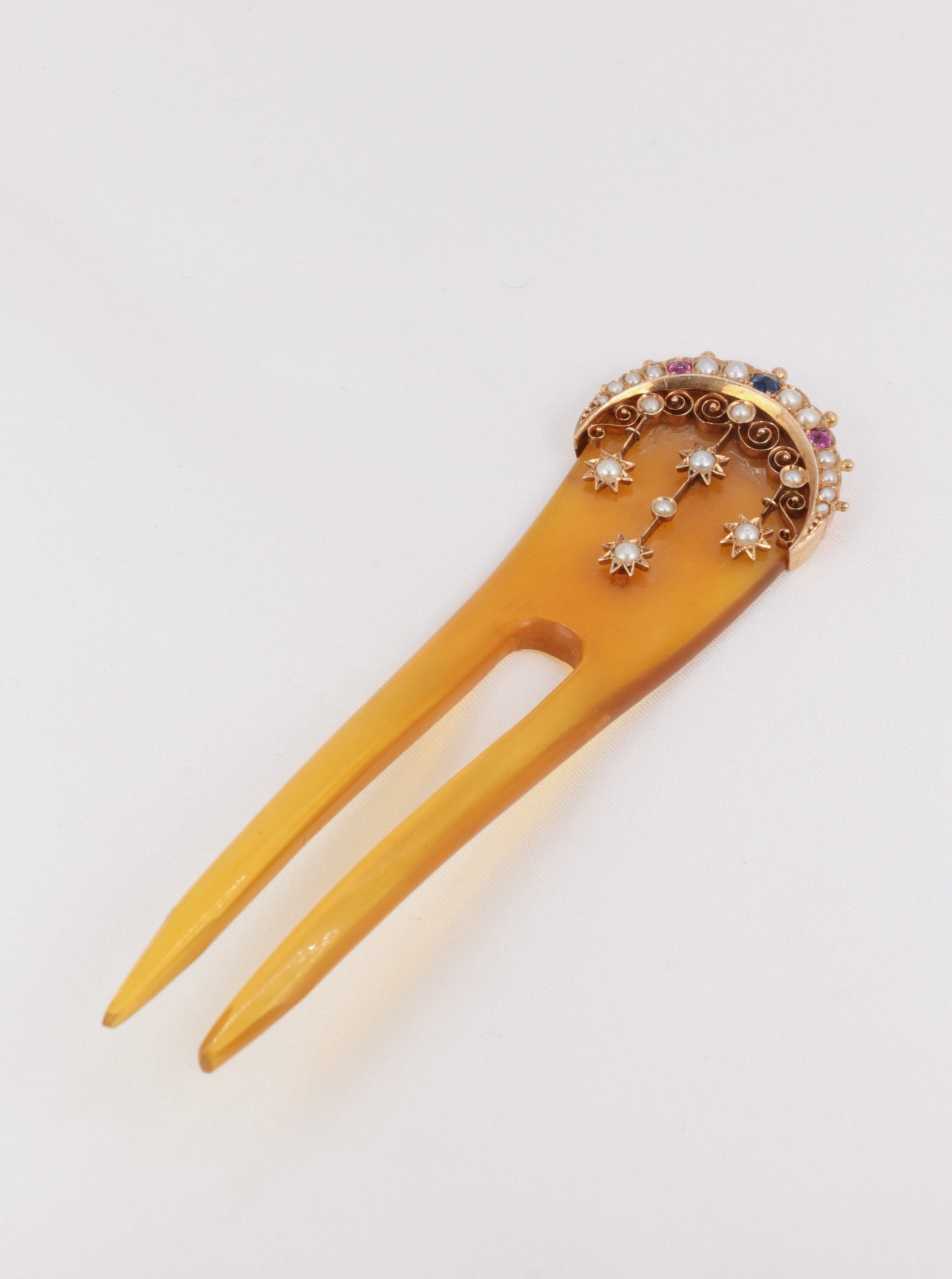 Peigne en corne et en or 18k (750°/°°) figurant un motif céleste (une lune et des étoiles) serti de perles fines, saphirs et rubis typiques des productions du XIXème siècle. Travail français ou anglais de la seconde partie du XIXème siècle.