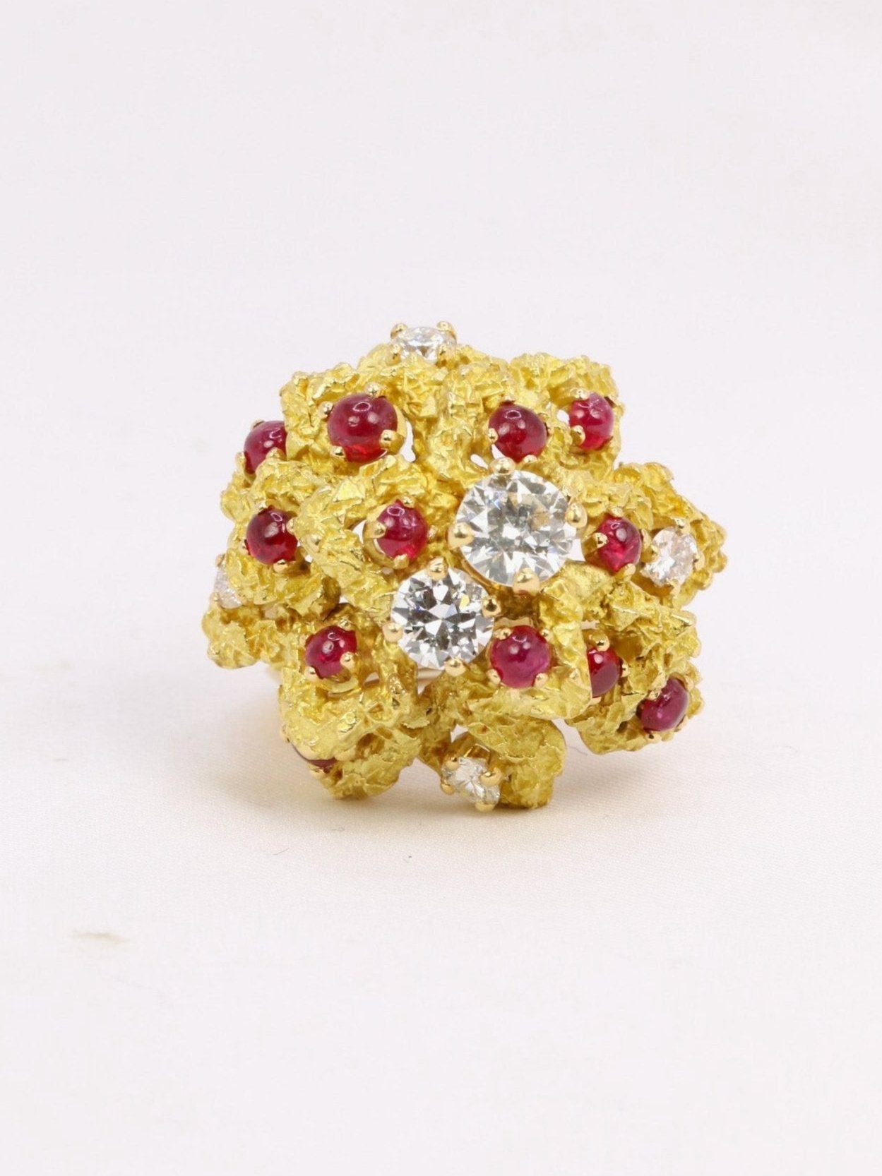 Bague cocktail vintage diamants cabochons de rubis

Bague en or 18k (750°/°°) composée d'un motif floral représenté par des pétales d'or amati et texturé rehaussés de cabochons de rubis de très belle couleur et de diamants taille moderne pesant 0,6 carat, 0,35 carat et 0,10 chacun carat pour les quatre plus petits. L'anneau est probablement rapporté. Travail français haute joaillerie des années 1970. Présence du poinçon tête d'aigle pour l'or 18 carats et trace de poinçon de fabricant (J un papillon ?).